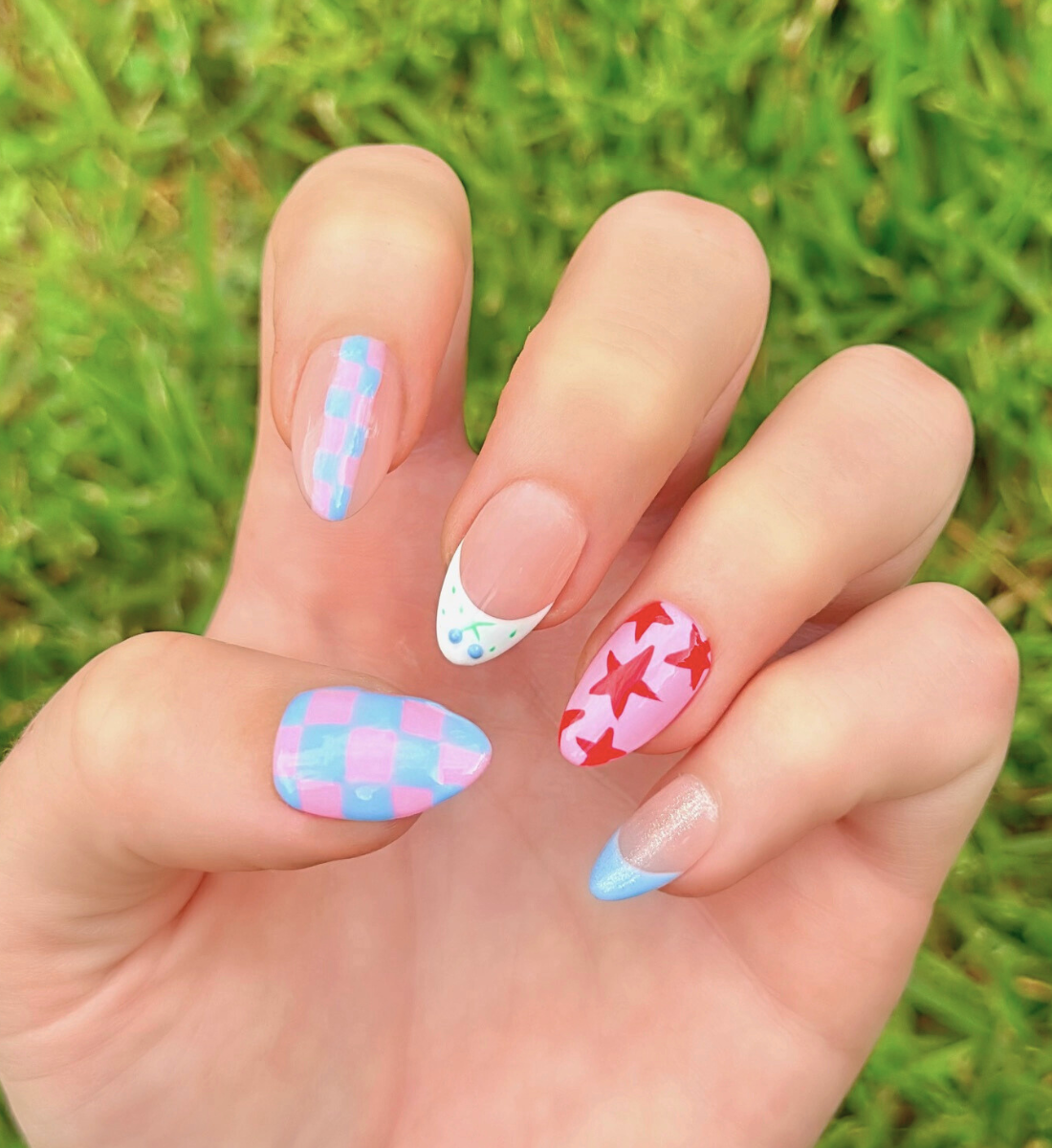 Colorful nail art with stars, checkers, and blueberries. Nail colors include light blue, red, and light pink.